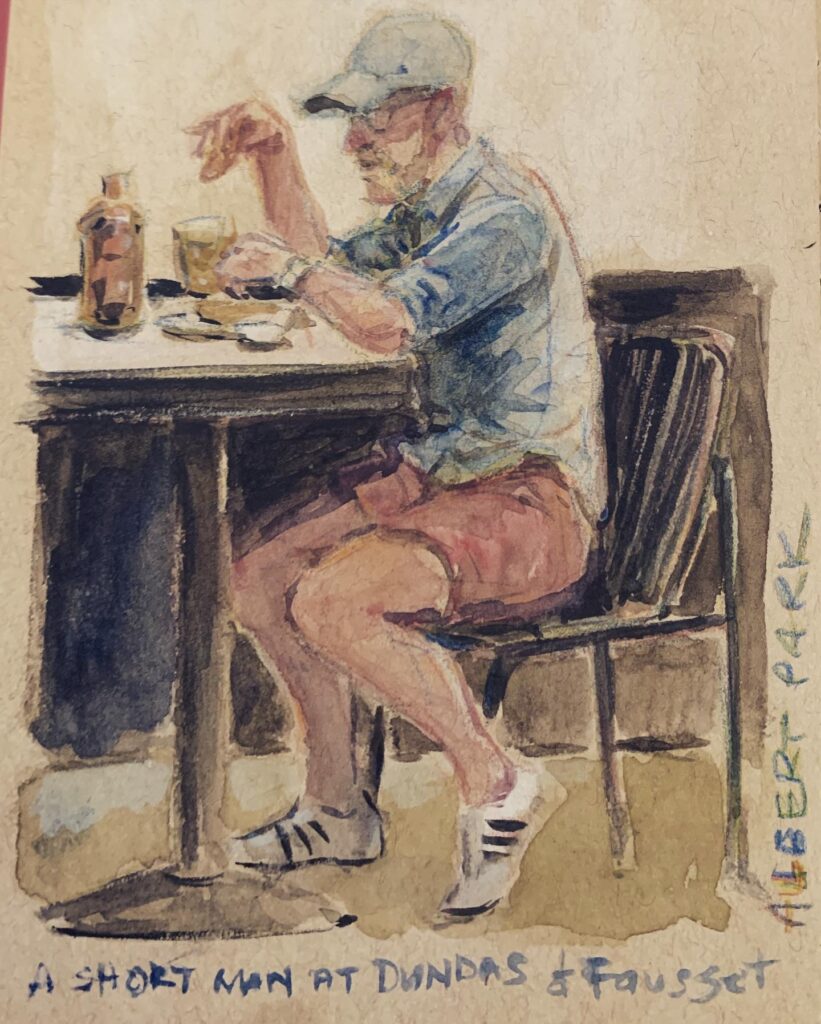 A short man at Dundas & Fausset. A white man with beard and glasses. Man wearing shorts and a baseball cap. Man sitting at a cafe outdoor table, having a meal. Albert Park, Melbourne, Australia. 2022 By Maria Pena, Artist and Illustrator. Also known as Maria de Los Angeles Pena. #Storyboarderau #storyboarder